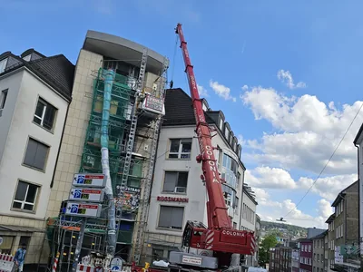 Baustelle mit Gerüst, Bauaufzug, Autokran und Absperrungen in der Innenstadt