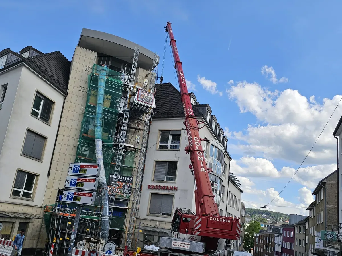 Baustelle mit Gerüst, Bauaufzug, Autokran und Absperrungen in der Innenstadt
