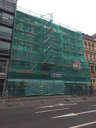 Fassadengerüst mit grünem Schutznetz an einem Geschäftshaus im Kölner Zentrum – Paul Gerüstbau