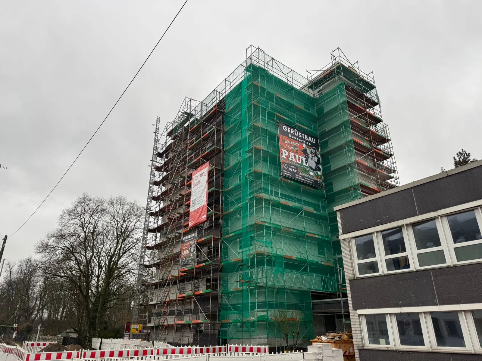 Hochhaus komplett eingerüstet und mit grünem Schutznetz verkleidet – Paul Gerüstbau