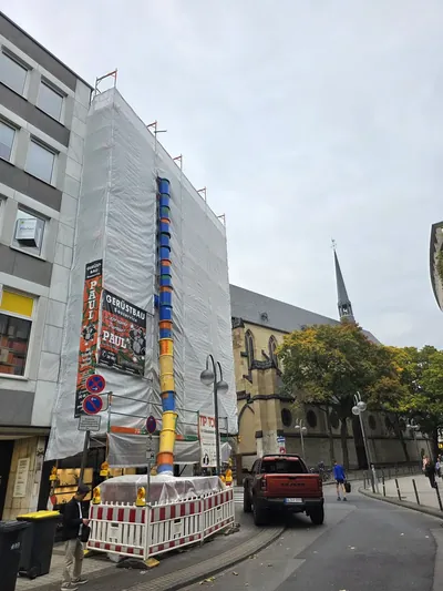 Vollflächig mit Planen eingehaustes Eckgebäude am Kolpingplatz in Köln mit Bauschuttrutsche