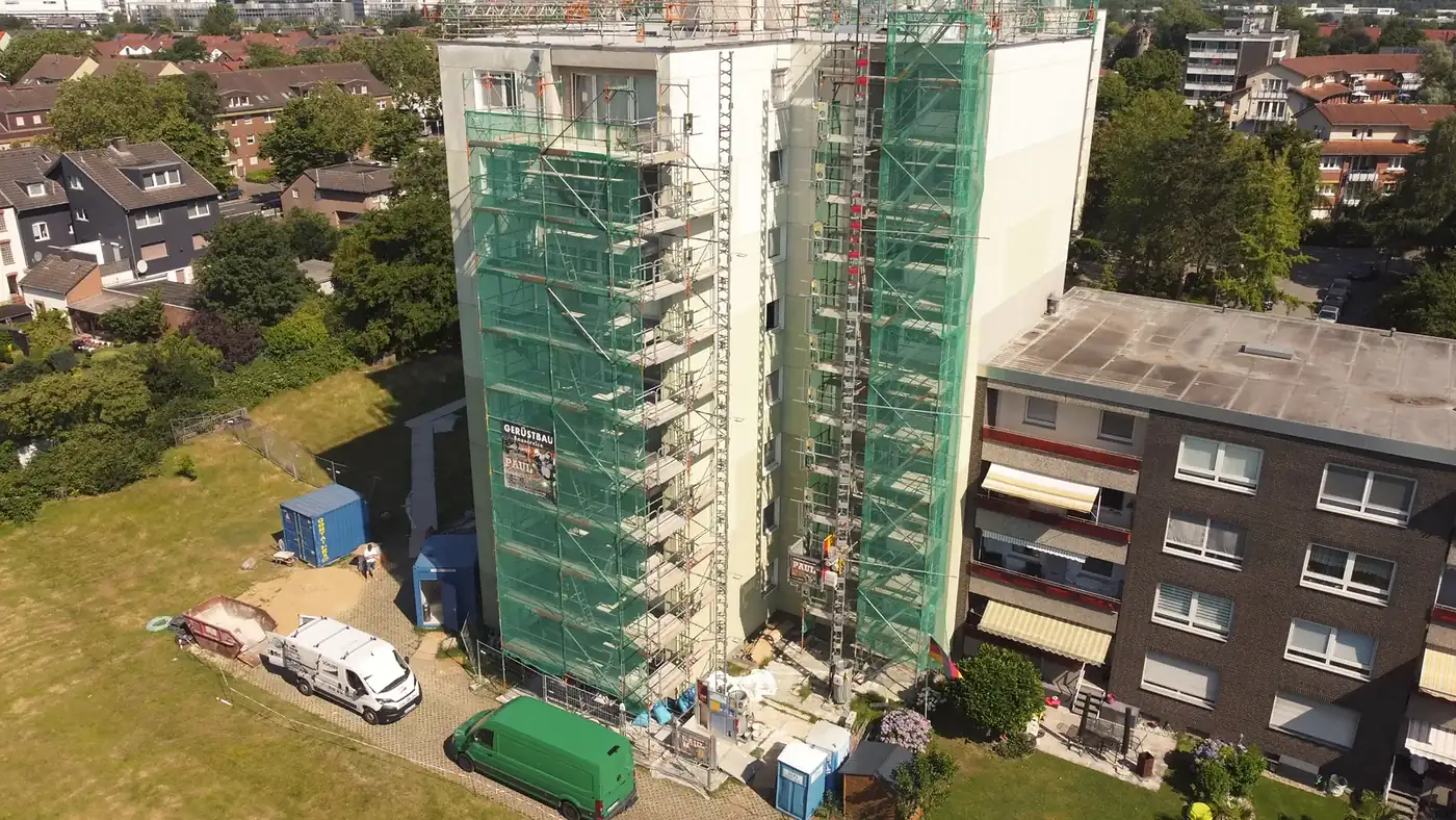 Eingerüstetes Wohnhochhaus einer Düsseldorfer Siedlung mit Schutznetz, Bauaufzug und Baustelleneinrichtung